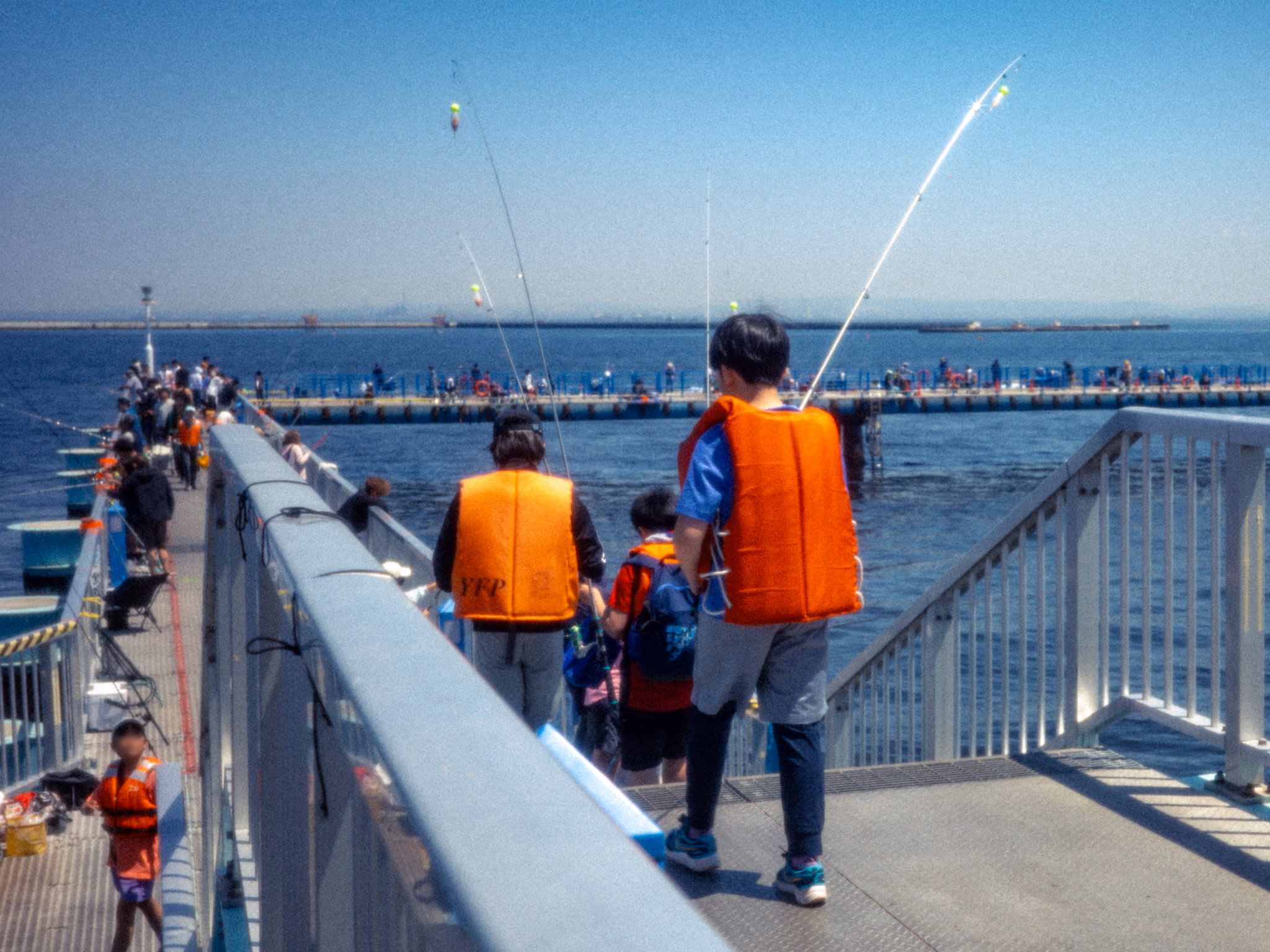 People in life vests walking along Honmoku Pier.